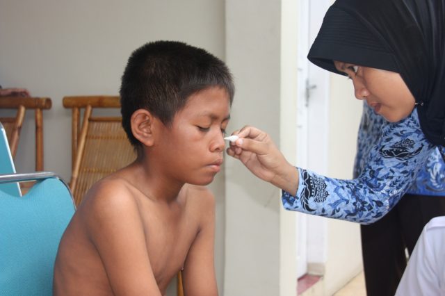 July, a health worker, treats Riduan, a person affected by leprosy